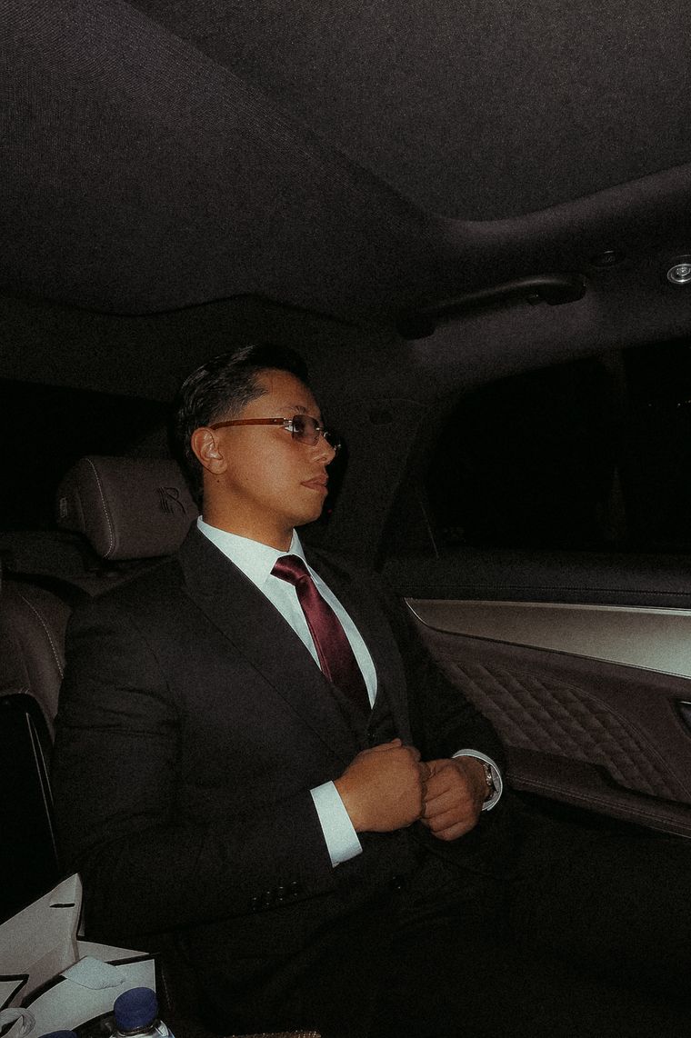 Hisham Alfar in a dark suit, seated in the back of a car at night