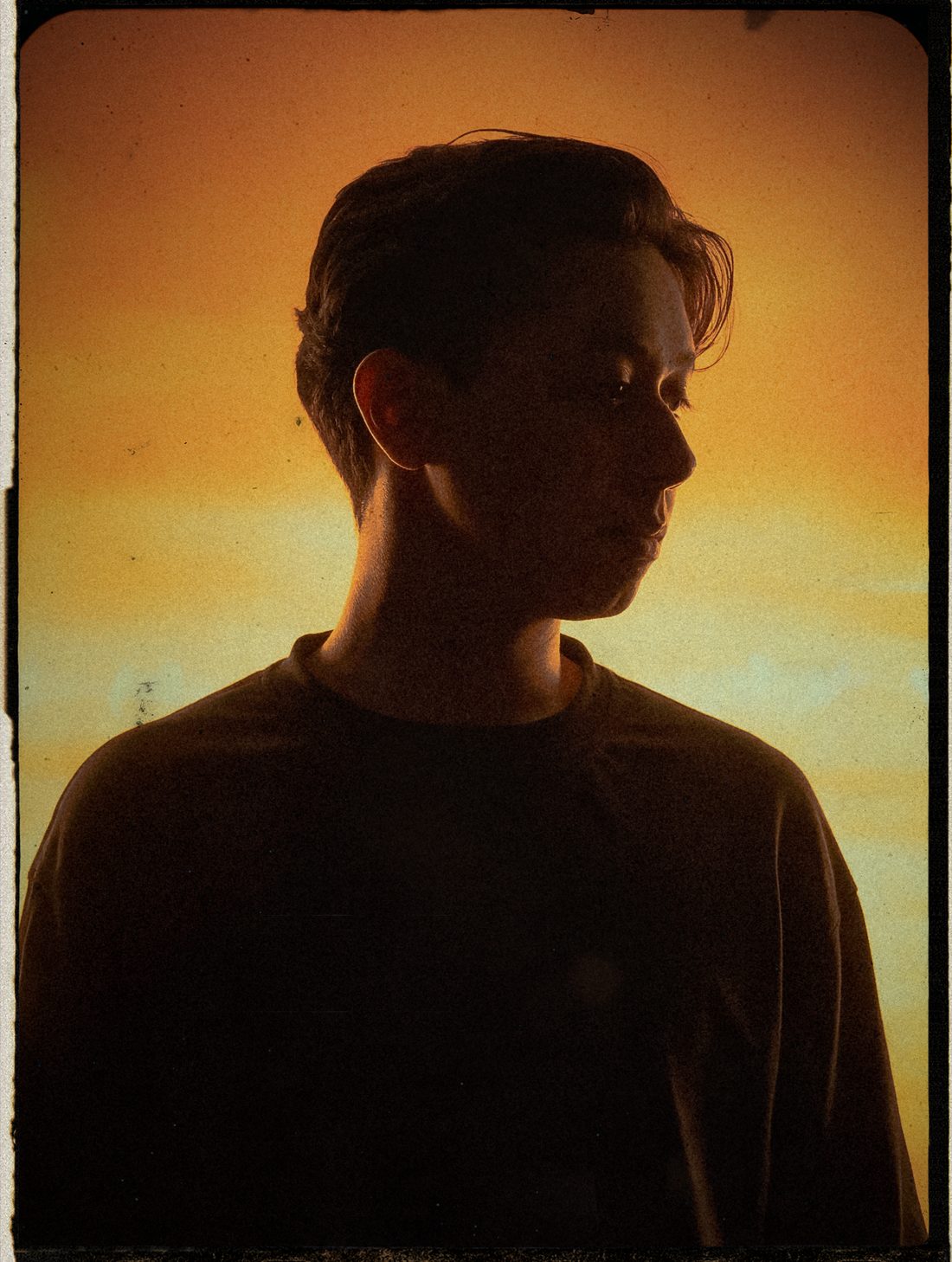Hisham Alfar, backlit in profile against an amber sky